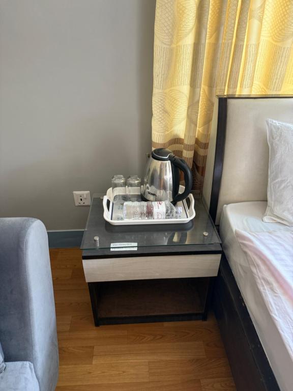a nightstand with a tea kettle on it next to a bed at Home Guest House in Kathmandu