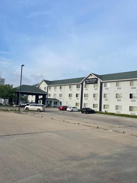 Un gran edificio blanco con coches aparcados en un estacionamiento. en New Victorian Inn & Suites Lincoln, en Lincoln