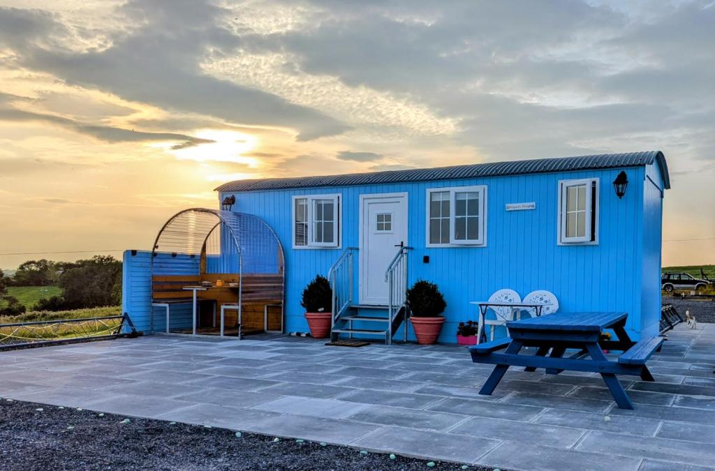 a blue tiny house with a picnic table and a bench at Shepard's Delight in Lisnaskea