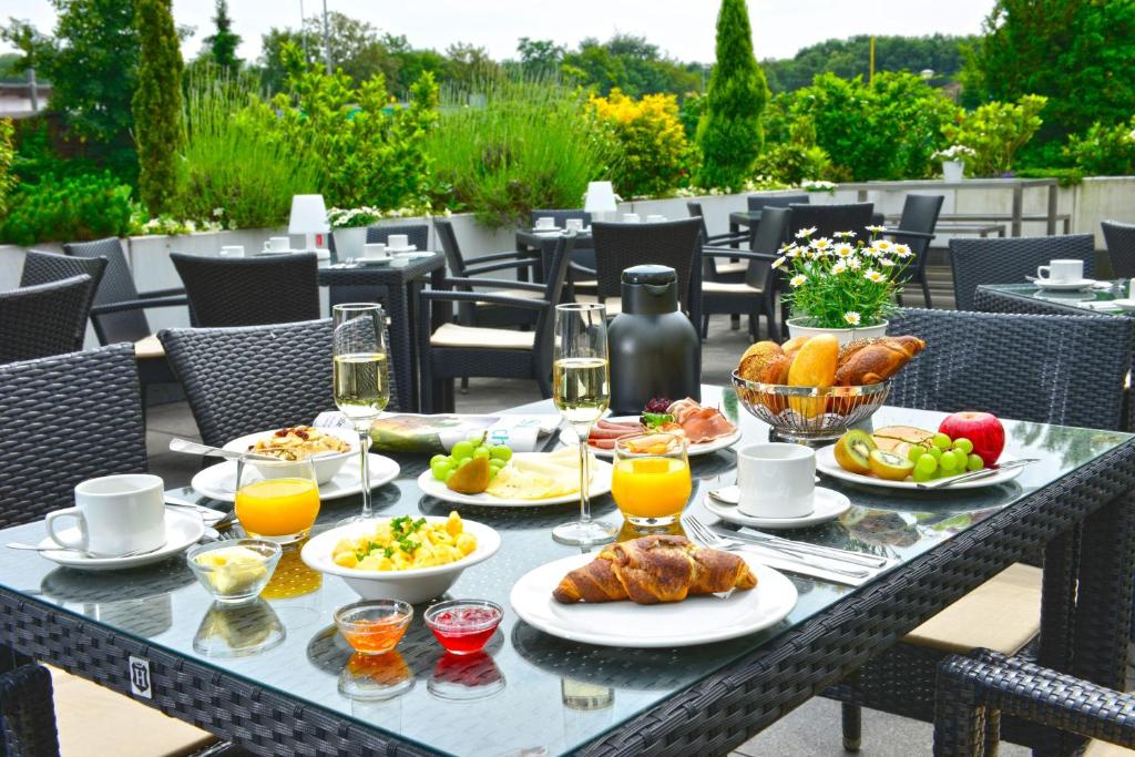 einen Tisch mit Speisen und Getränken auf einer Terrasse in der Unterkunft Parkhotel Oberhausen in Oberhausen