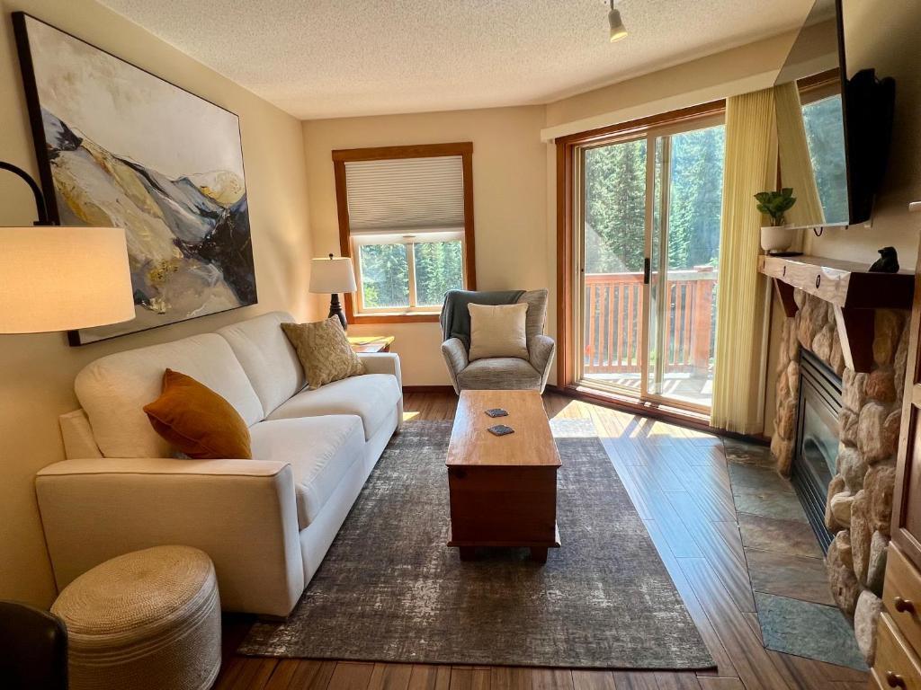 a living room with a white couch and a fireplace at Main Village, Ski-in Ski-out, Hot Tub, Condo in Sun Peaks
