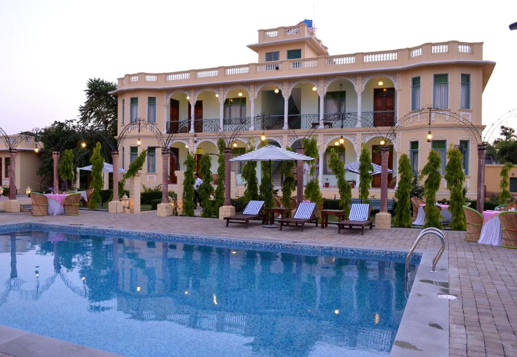 a hotel with a swimming pool in front of a building at Koolwal Kothi Zinc Journey by The Fern, Nawalgarh, Rajasthan in Nawalgarh