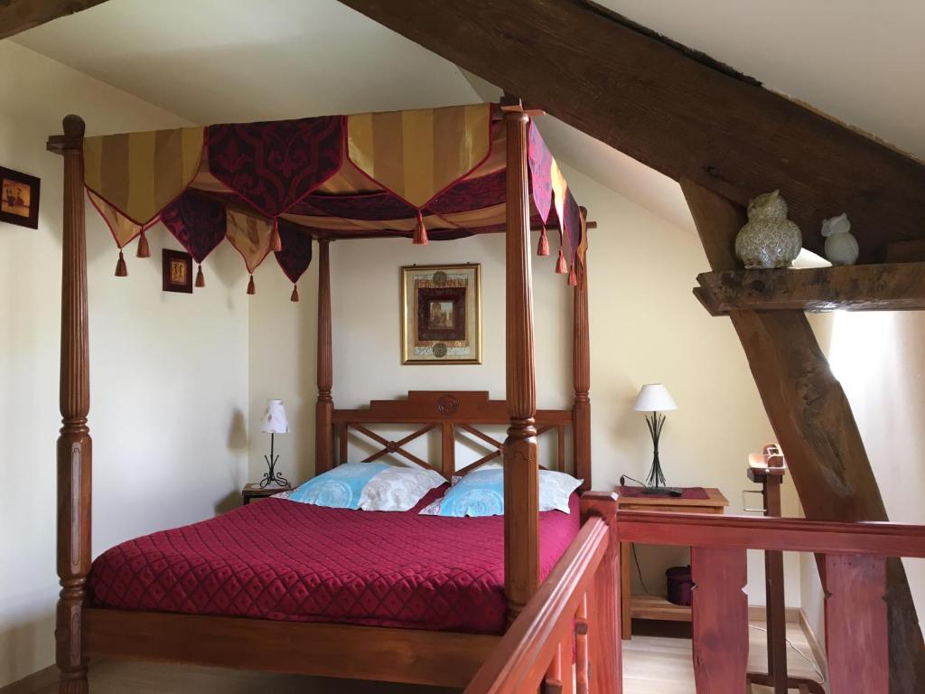 sypialnia z łóżkiem z baldachimem i czerwoną narzutą w obiekcie La Pomme de nuit w mieście Bayeux