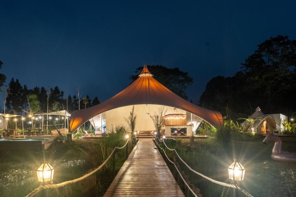 a wooden walkway with a large tent at night at Sanctua Luxury Glamping Resort in Bedugul