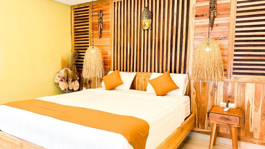a bedroom with a bed with white sheets and orange pillows at Tropical Boho Loft Villa with Sofa Beds in Canggu