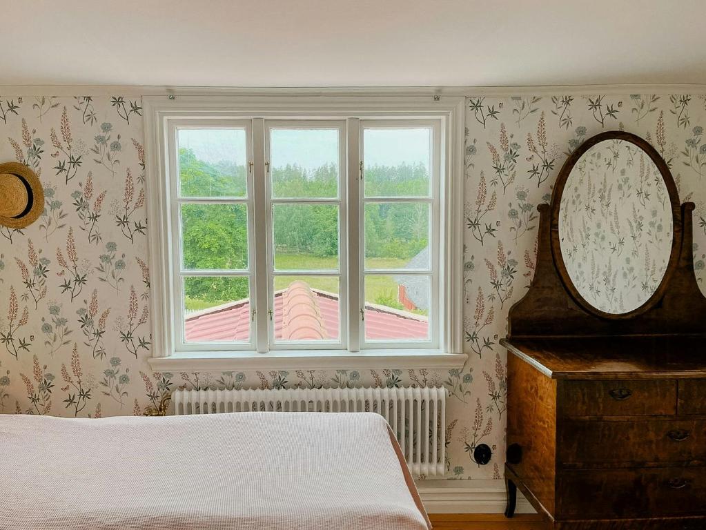 a bedroom with a bed and a mirror and a window at Historic Countryside Home Near Lake In Ekeryd in Svängsta