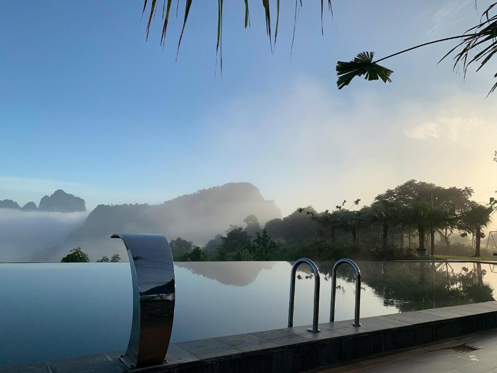 une piscine avec deux chaises au bord de l'eau dans l'établissement La Montana De Luong Son, à Chân Miên