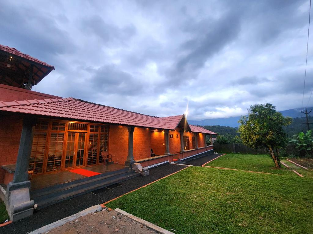 a building with a red roof and a grass yard at Mana Gramam Resort Mudumalai in Mudumalai National Park