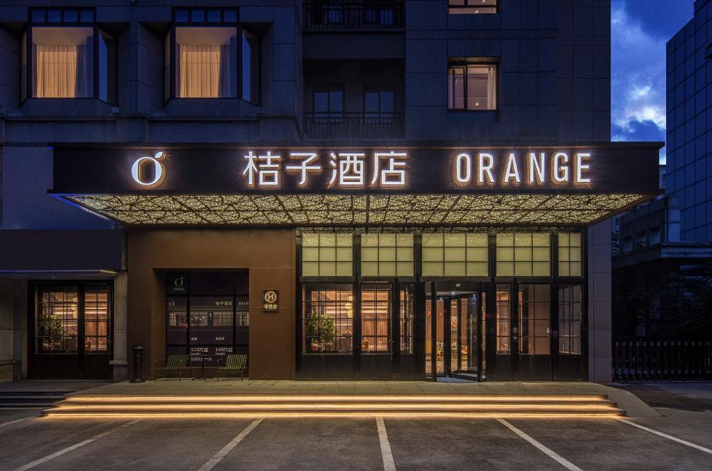 een kantoorgebouw met een bord waarop oranje staat bij Orange Hotel Qingdao Chengyang MixC in Qingdao