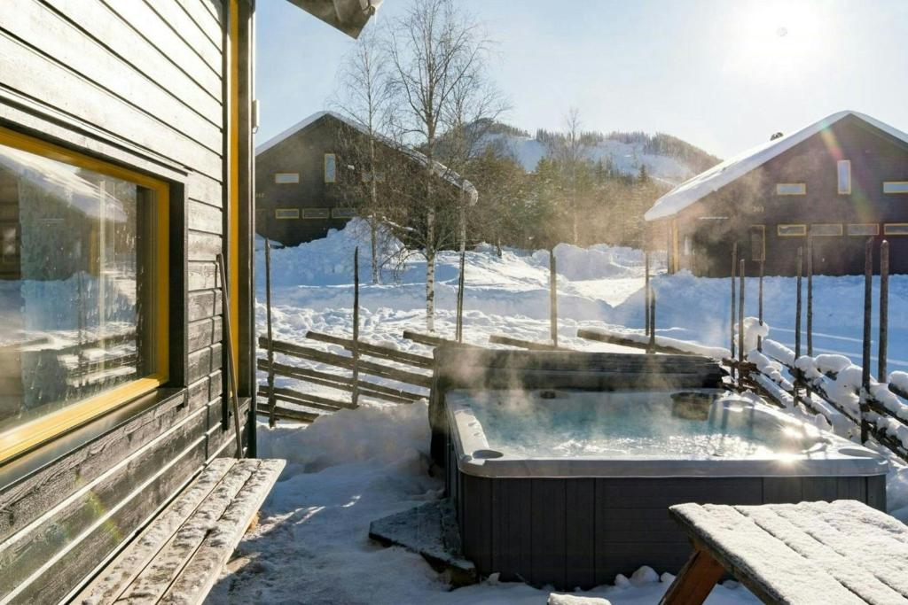 a hot tub on the side of a house in the snow at Spacious Mountain Cabin With Jacuzzi In Kläppen in Transtrand