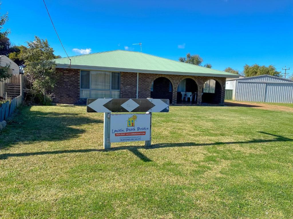 a sign in the grass in front of a house at Lancelin Beach house in Lancelin