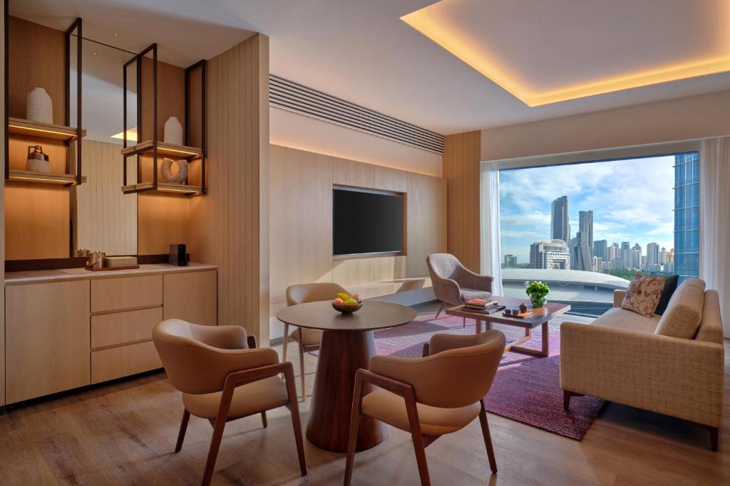 A generous sitting area opens toward a floor-to-ceiling skyline window.