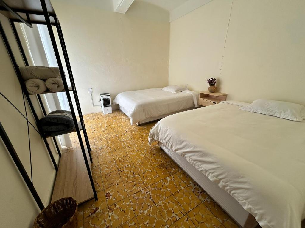une chambre d'hôtel avec deux lits et un miroir dans l'établissement Independencia 106 - Una casa cómoda en el centro historico de Oaxaca, à Oaxaca