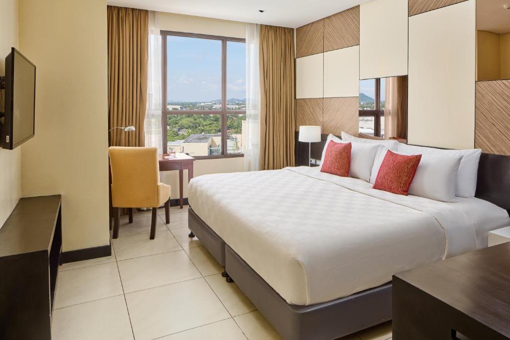 Una habitación de hotel con una cama grande y un escritorio. en Summit Hotel Tacloban, en Tacloban