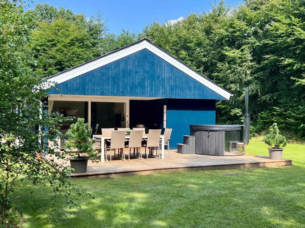 a blue building with a deck with chairs and a grill at Renovated Holiday Home By Kvie Lake in Ansager