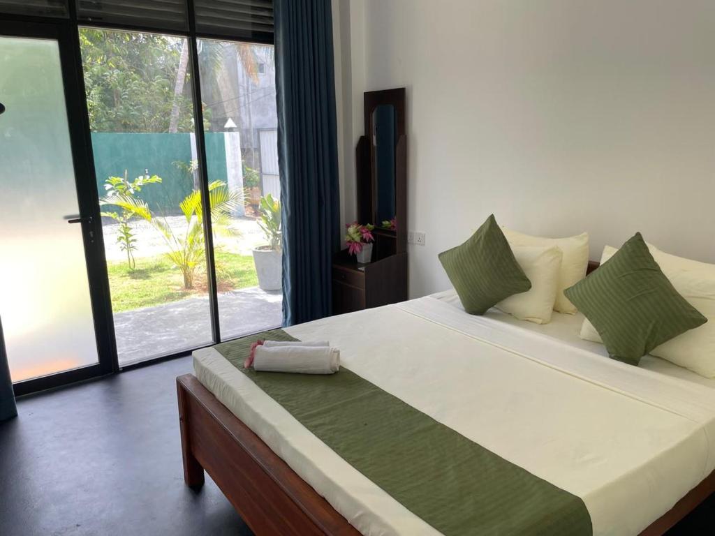 a bedroom with a large white bed with green pillows at The Pearl Safari Resort in Udawalawe