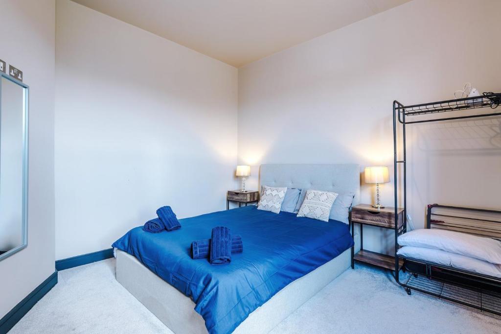 a bedroom with a blue bed with two bags on it at Bright Flat with Wifi, Close to Beach! in Wallasey