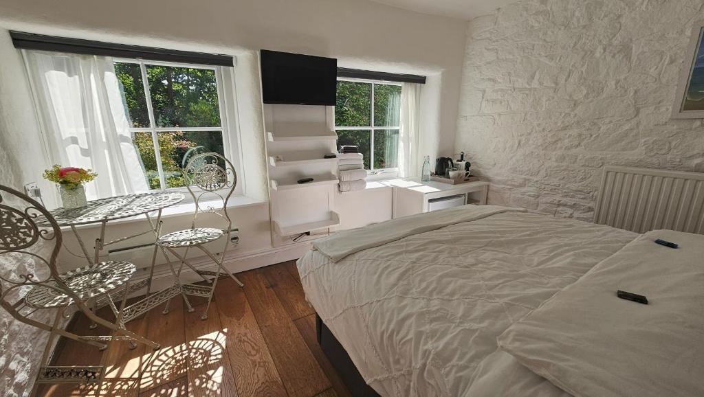 a bedroom with a bed and a desk and a table at Primrose Cottage peaceful room and private garden in Helston