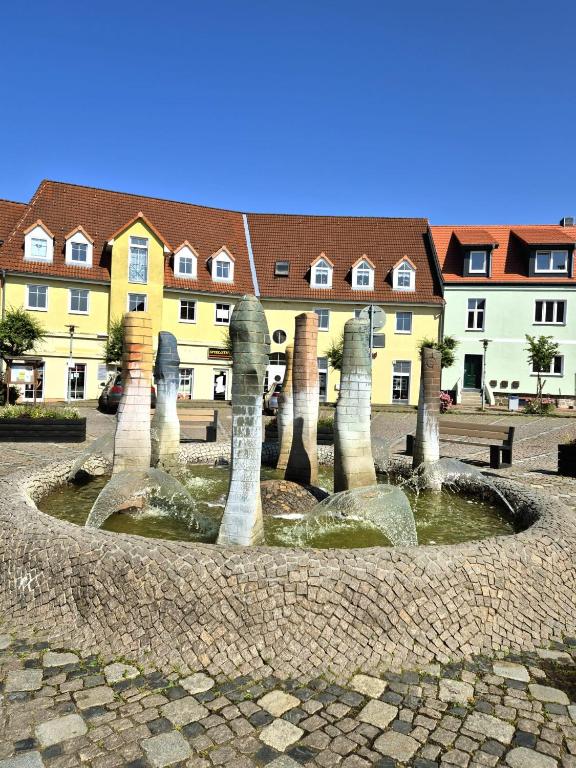 a fountain in the middle of a courtyard with houses at Ferienidyll an der Recknitz in Tessin