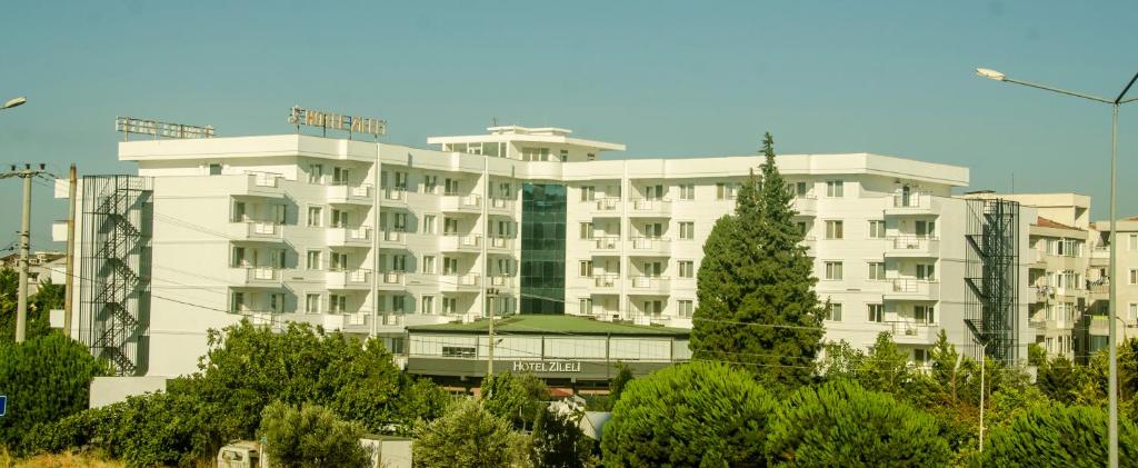 a large white building with trees in front of it at Zileli Suıtes in Hamidiye