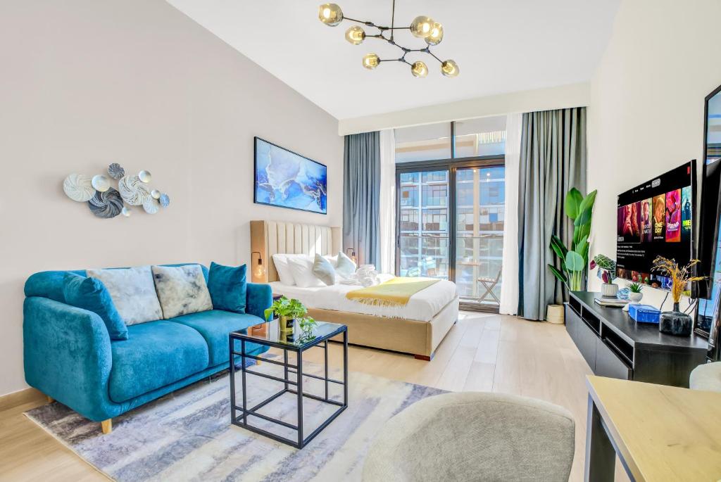 ein Wohnzimmer mit einer blauen Couch und einem Fernseher in der Unterkunft Elegant Studio with Pool Access & Private Terrace in Dubai
