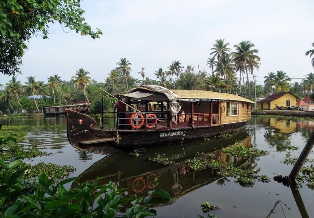 a boat on a river with palm trees in the background at One Bed Room Houseboat in Kumarakom