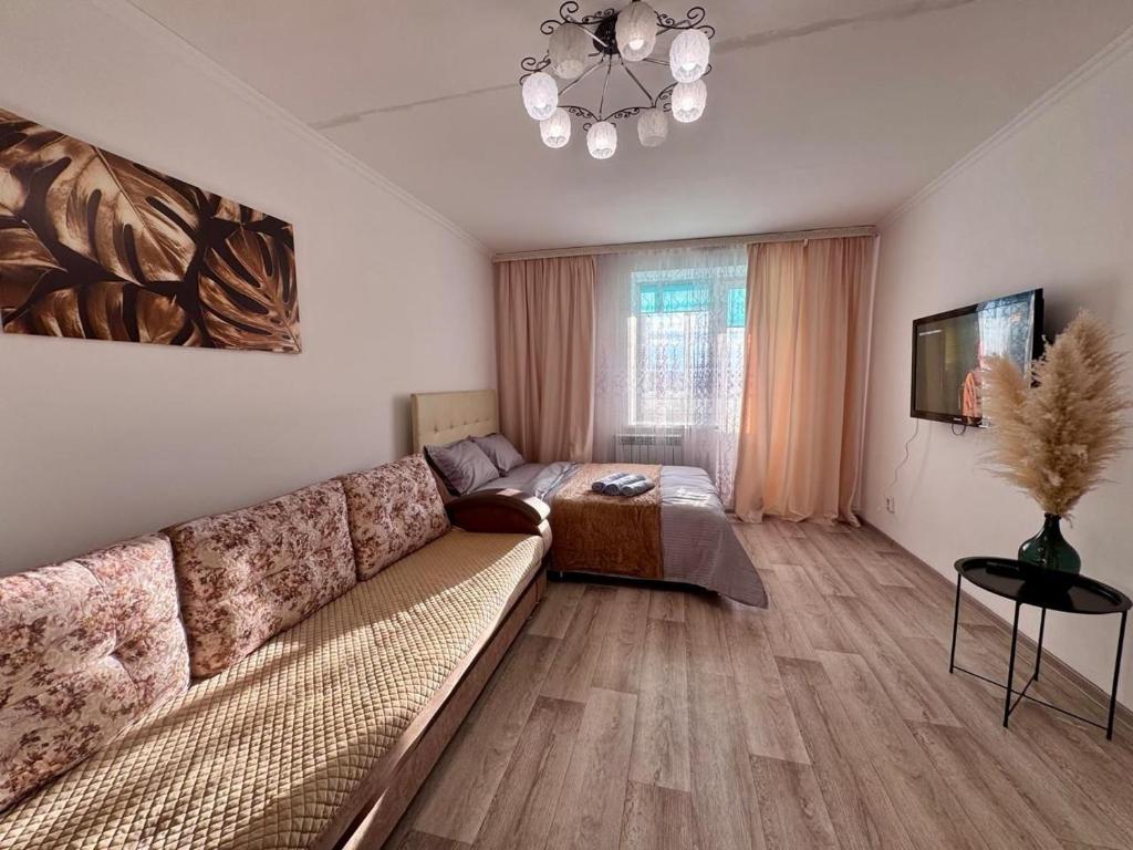 a living room with a couch and a television at Квартира рядом с Усолкой Сатпаева 348 in Pavlodar