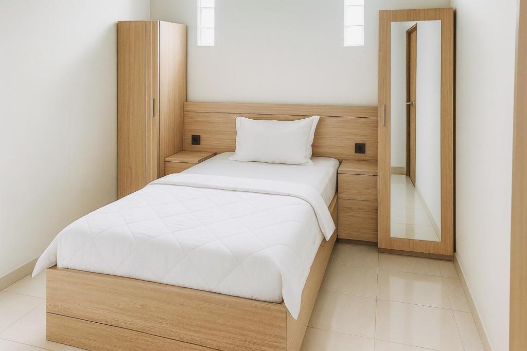 a small bedroom with a bed and a mirror at House of Felix - Surabaya Guest House in Surabaya