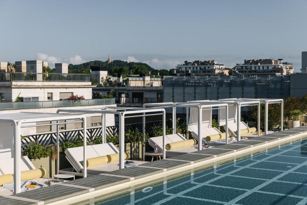 a swimming pool with lounge chairs on the roof of a building at The Social Hub San Sebastián in Donostia-San Sebastián