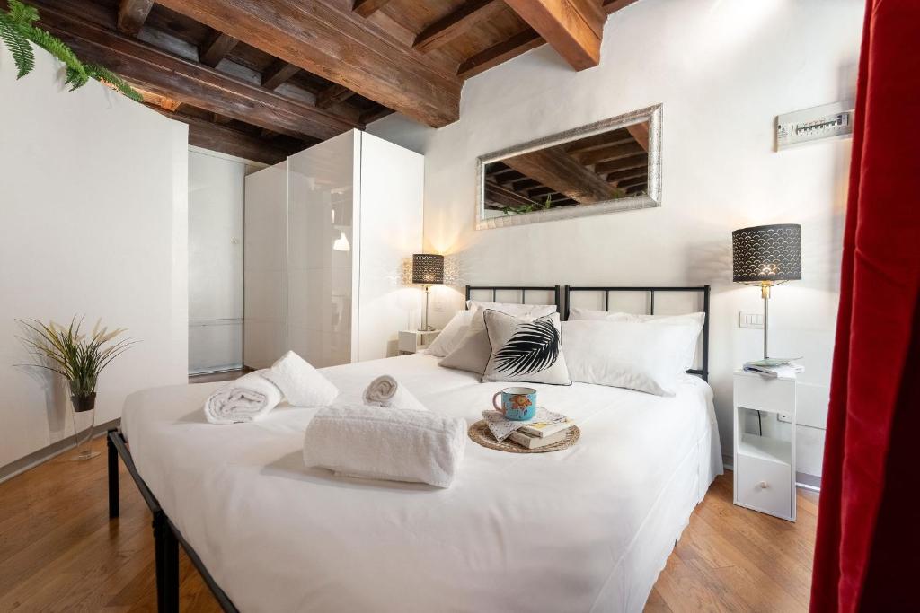 una camera da letto con un grande letto bianco con asciugamani sopra di Keys of Italy - Rustici 3 - Charming 1BR Loft a Firenze