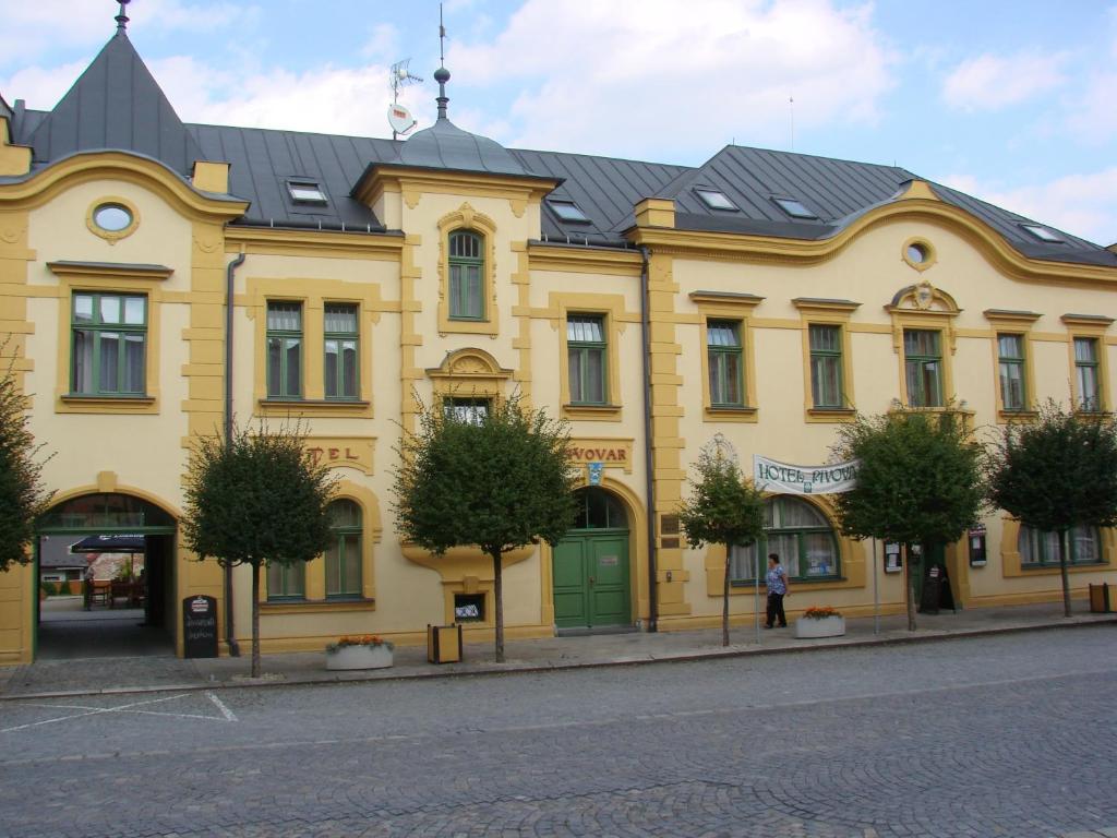 a yellow building with a black roof on a street at Pivovarský Hotel in Kojetín