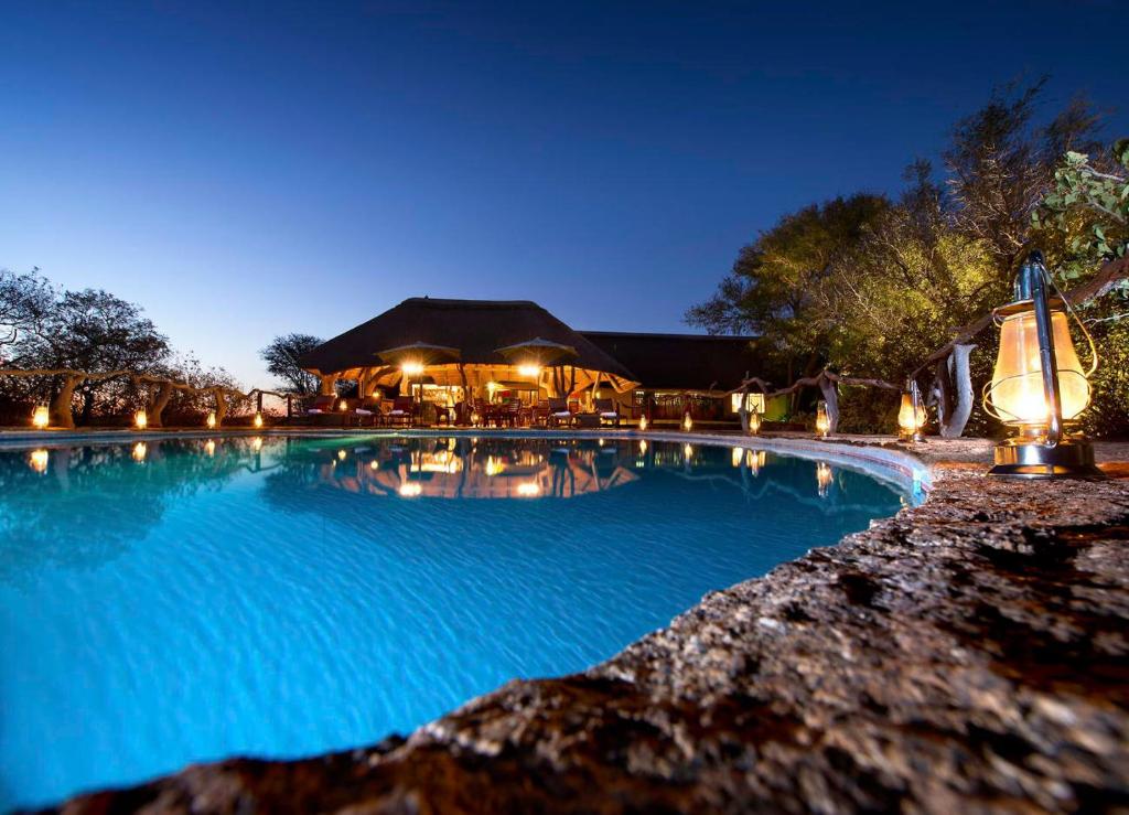 a swimming pool at night with a building in the background at Sable Ranch Thaba Khaya Lodge in Brits