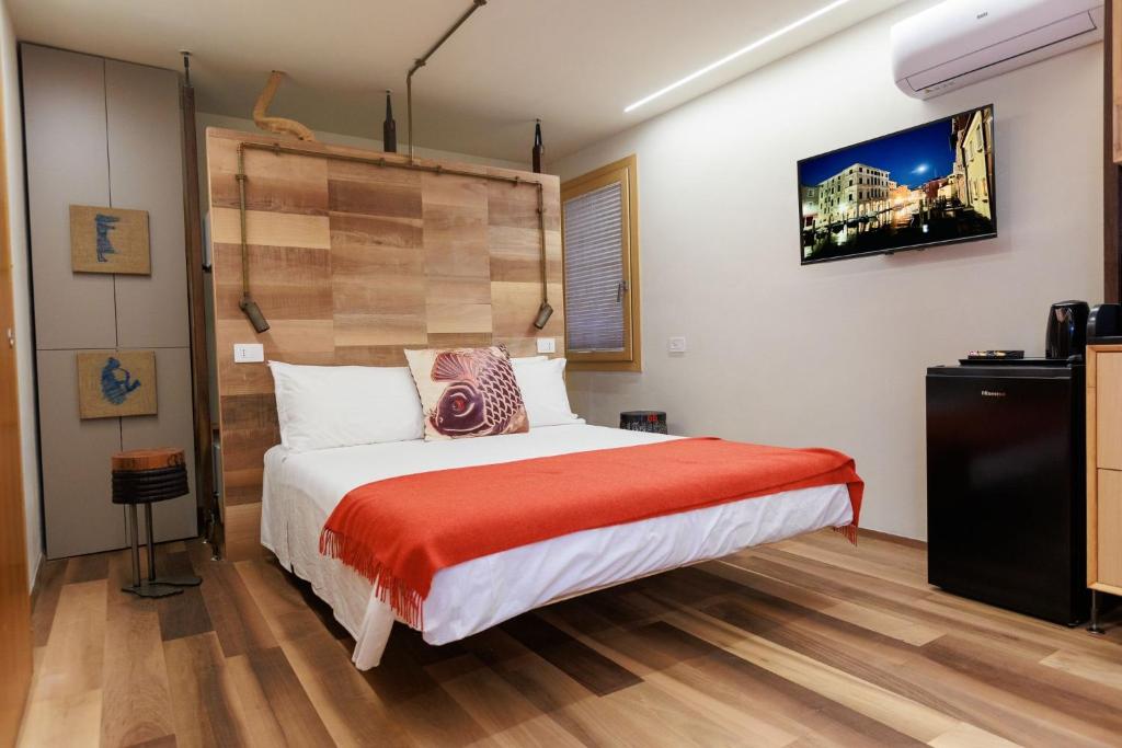 a bedroom with a bed with a red blanket at LE RIVE Guest House La Ciosà in Chioggia