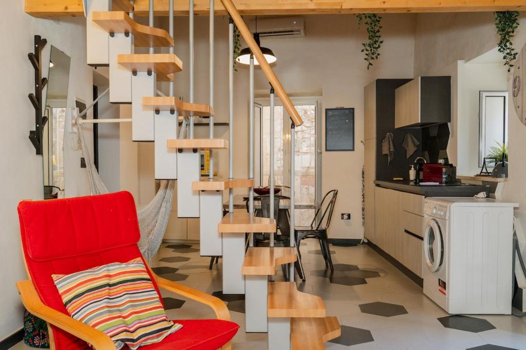 a living room with a red chair and a kitchen at Naiadi Giudecca in Siracusa