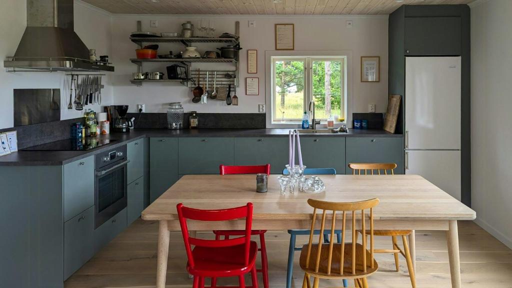 a kitchen with a wooden table and red chairs at Charming Cottage Near Sea On Fårö in Fårö