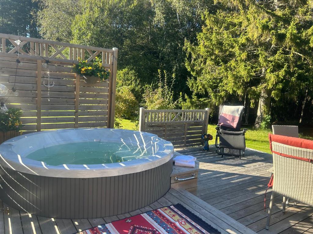 a hot tub on a deck with a chair at The Blomsholm Cabin - Recharge Your Electric Car in Strömstad