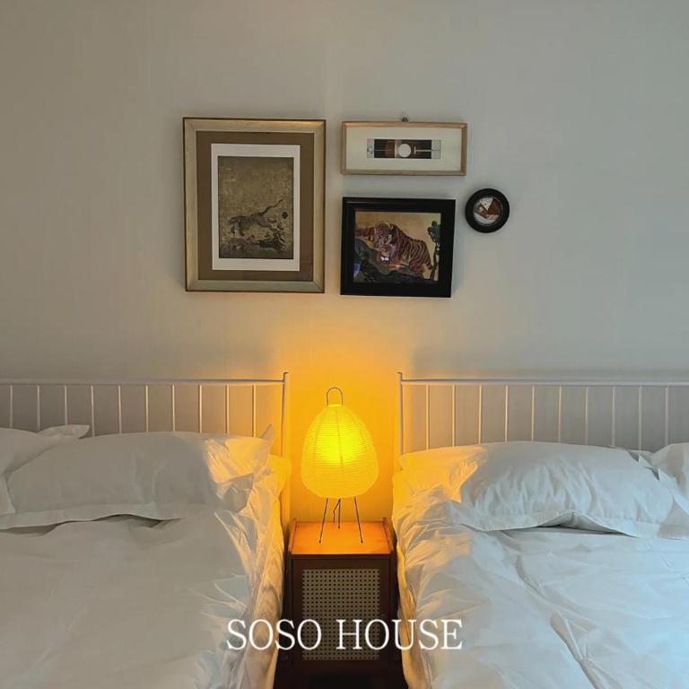 a bedroom with two beds and a lamp on a night stand at 소소 하우스 in Seoul