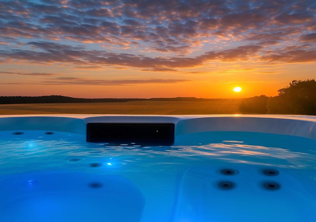 un bain à remous avec un coucher de soleil en arrière-plan dans l'établissement Private Scandinavian Villa with Jacuzzi, Fireplace and Luxury Breakfast near Lund and Malmö, à Kävlinge