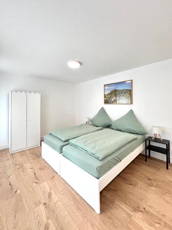 a white bedroom with a bed and a table at Privatzimmer in Apartment Brunnenstraße Braubach in Braubach