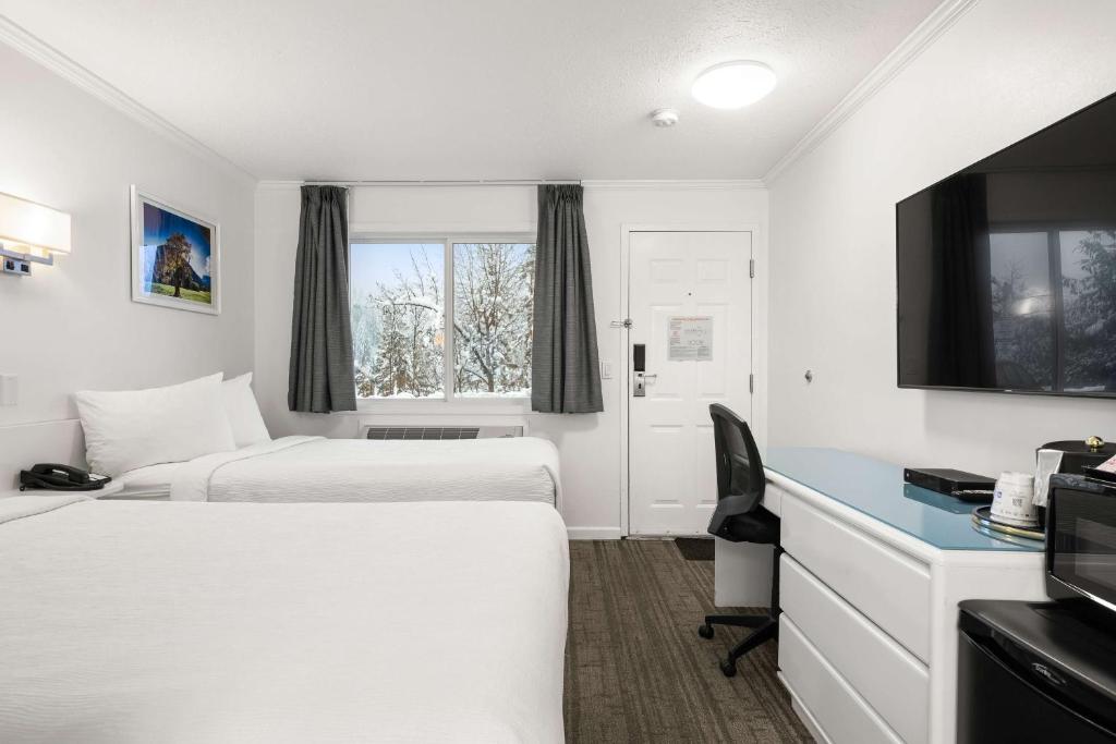 a hotel room with two beds and a flat screen tv at SureStay Hotel by Best Western Rossland Red Mountain in Rossland