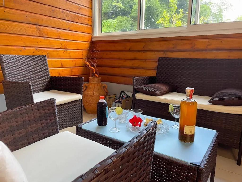 a patio with two chairs and a table with drinks at Appartement spacieux à Sainte-Rose, 70 m² avec jardin in Sainte-Rose