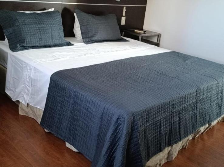 a large bed with a blue blanket on it at Suíte em Hotel de Luxo Bourbon in Belo Horizonte