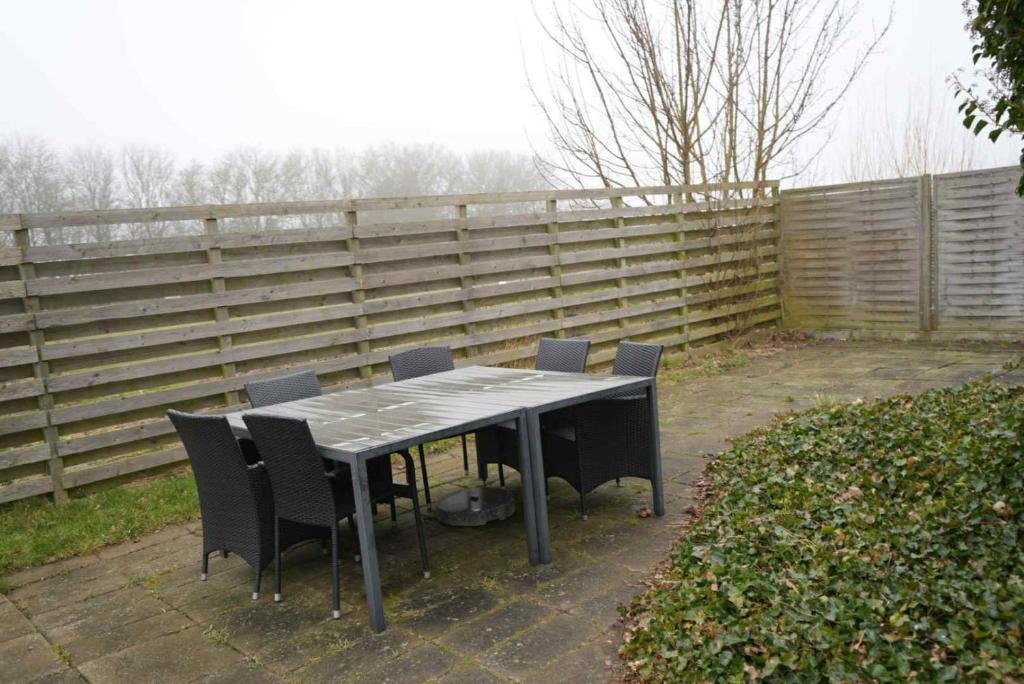 a table and chairs in a backyard with a fence at Slava Hygge Rooms in Nakskov