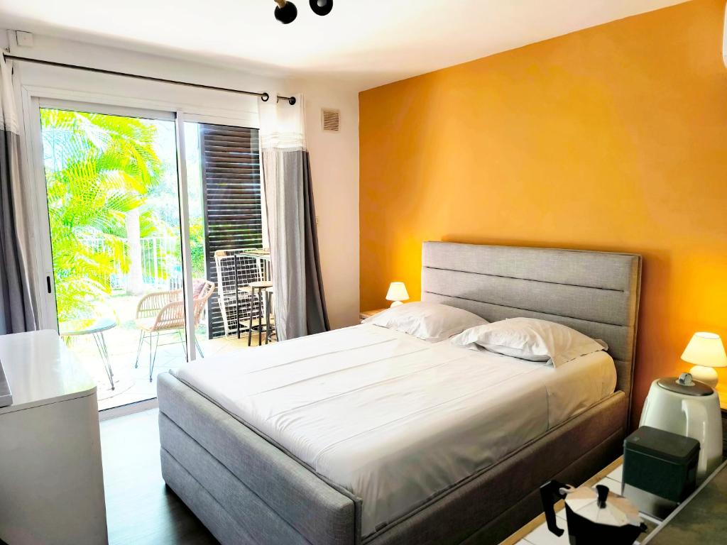 a bedroom with a large bed and a balcony at Le Soa - Studio - Jardin - Piscine in Saint-Gilles les Bains