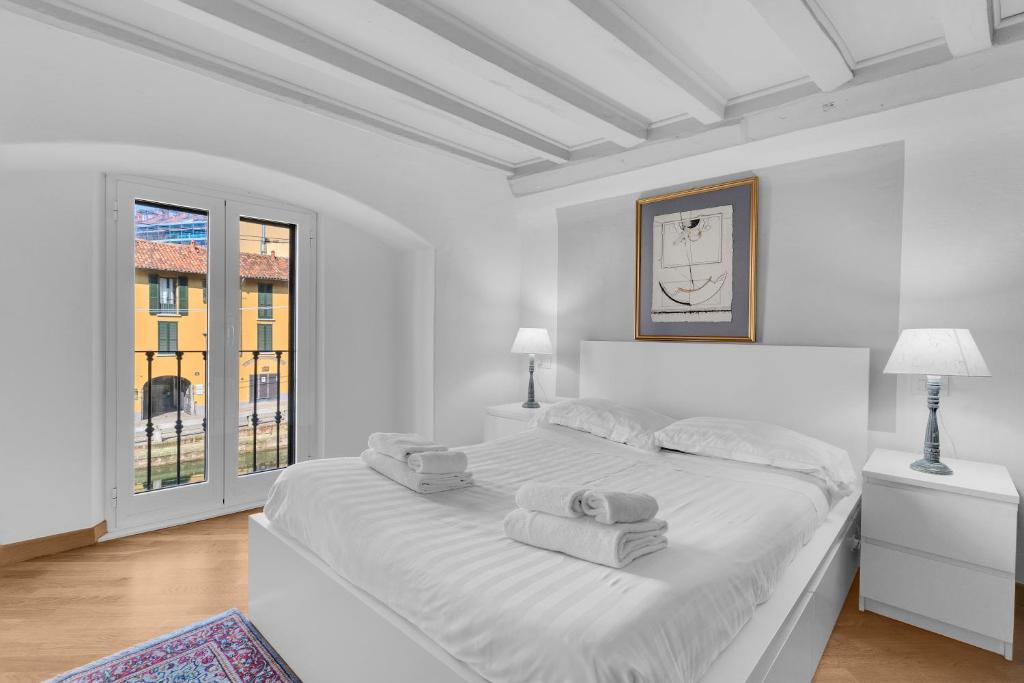 a white bedroom with a large bed and a window at The house of Ripa di porta ticinese 13 in Milan