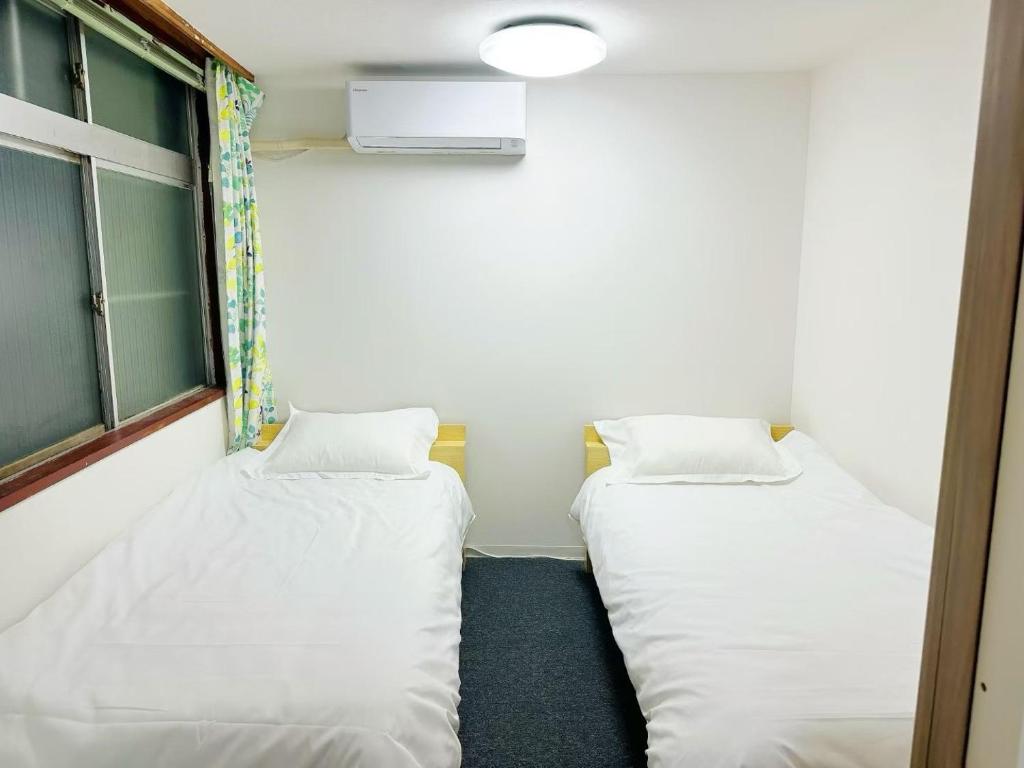 東京にある文京house103の白いシーツが敷かれた部屋にベッドが2つ