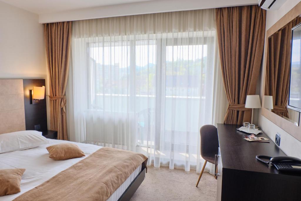 a hotel room with a bed and a desk and a window at Hotel Regal in Braşov