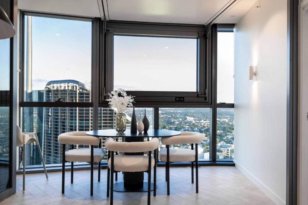 a dining room with a table and chairs and large windows at 1Bedroom Apt in Queen's Wharf lv 62 - Skyline and City view in Brisbane