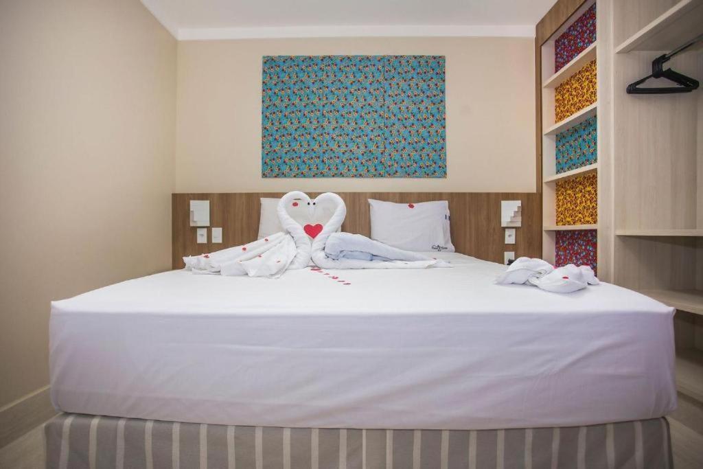 una camera da letto con un letto bianco con asciugamani sopra di CALDAS NOVAS - COM ACESSO GRATUÍTO Ao ACQUA PARK a Caldas Novas