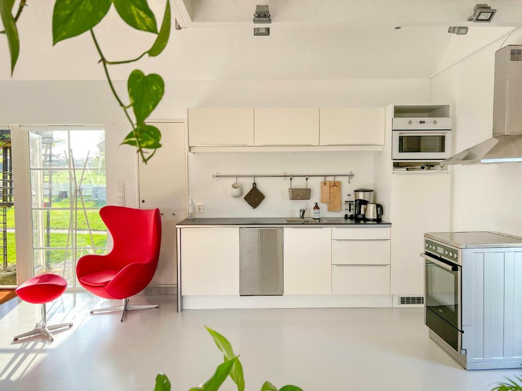 a kitchen with white cabinets and a red chair at Lovely "Studio Solbakke" At Asmaløy, Hvaler in Rød